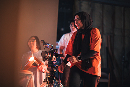 An SFSU media studies student filming on stage.